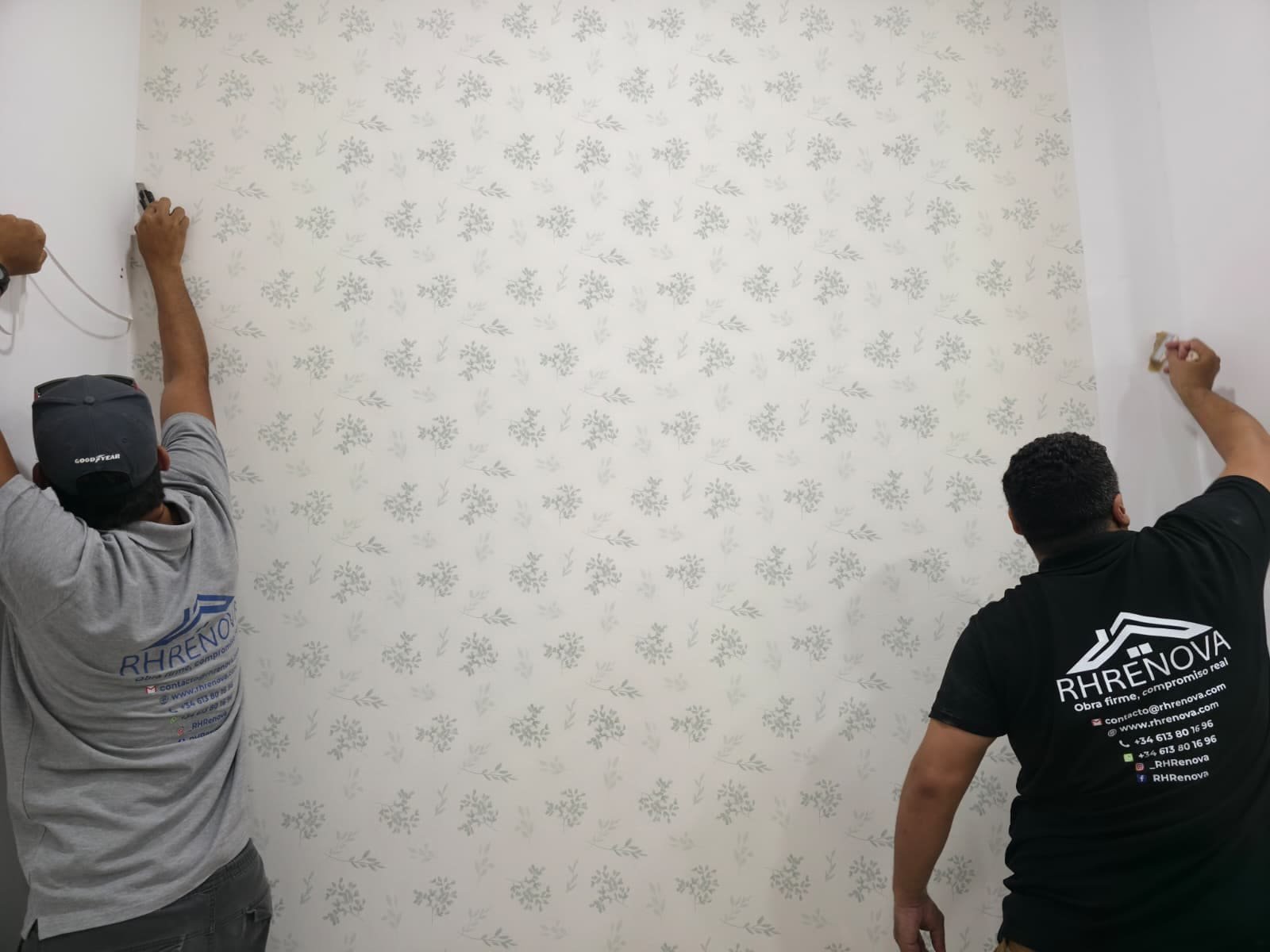 Pared con papel pintado floral terminada, vista de la esquina y del rodapié