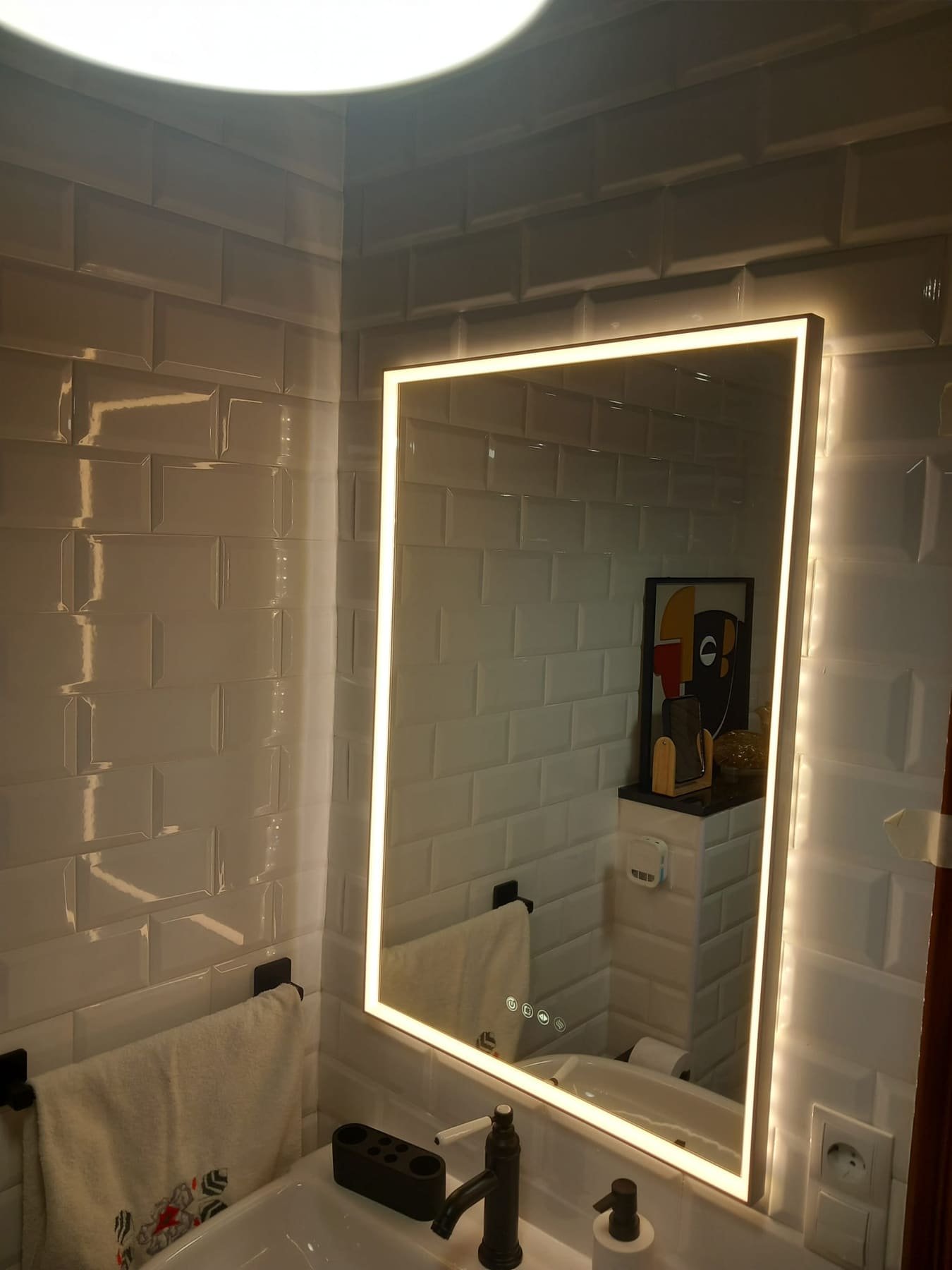 Espejo retroiluminado sobre azulejo metro blanco en un baño reformado