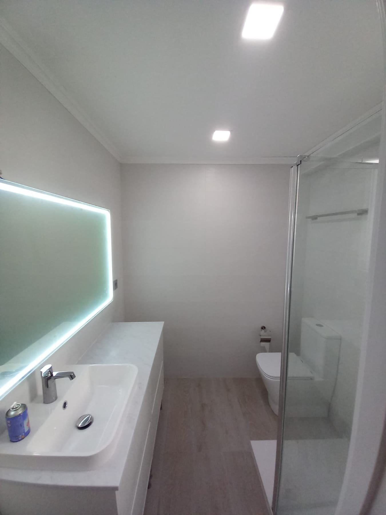 Baño reformado con bañera, espejo retroiluminado alargado y ducha independiente